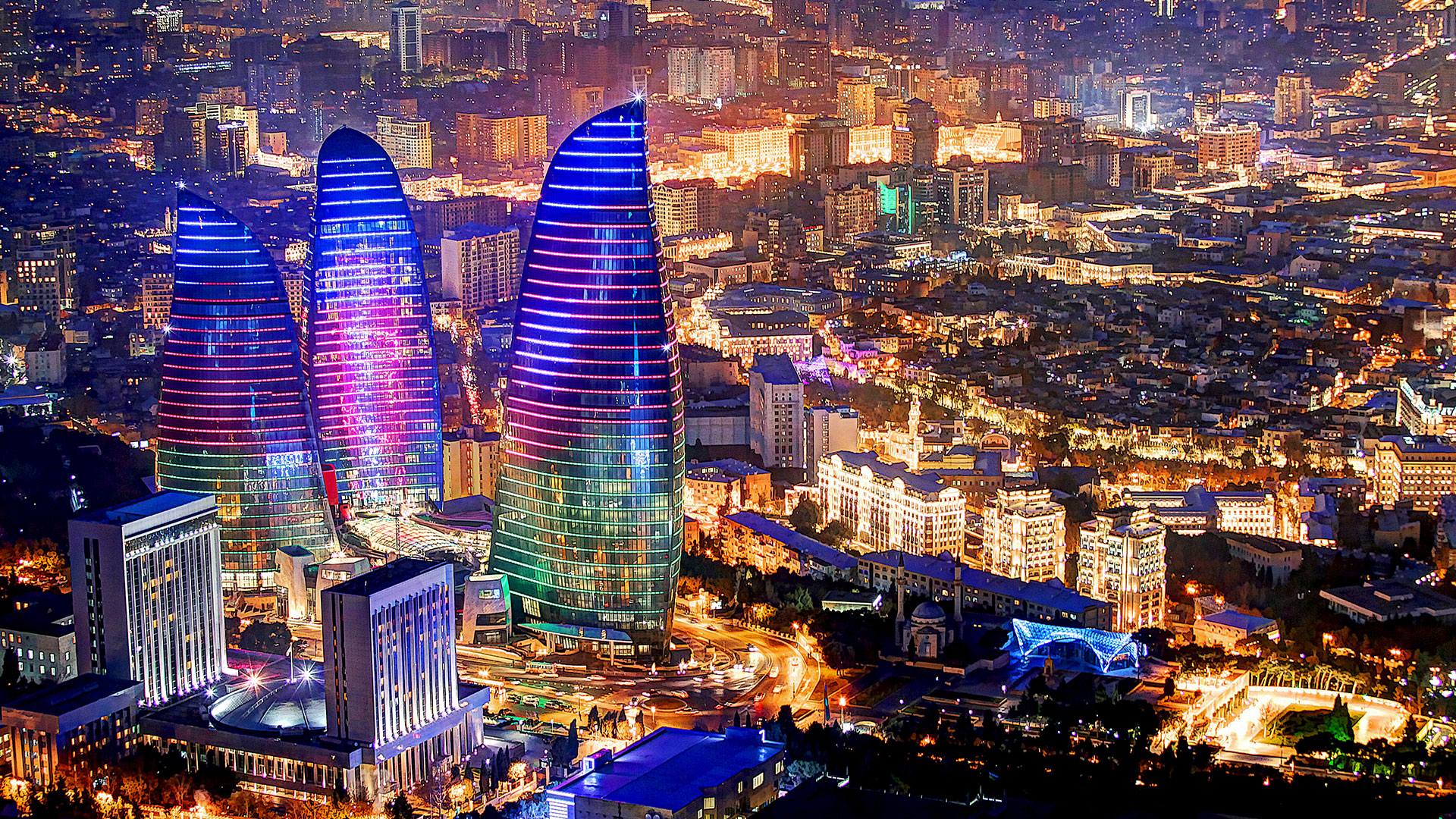 Baku city skyline at night with Flame Towers illuminated reflecting on the Caspian Sea
